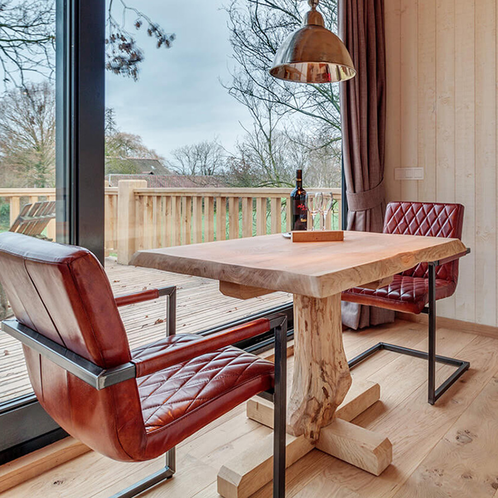 Twee stoelen met een houten tafel van een boomstam gemaakt